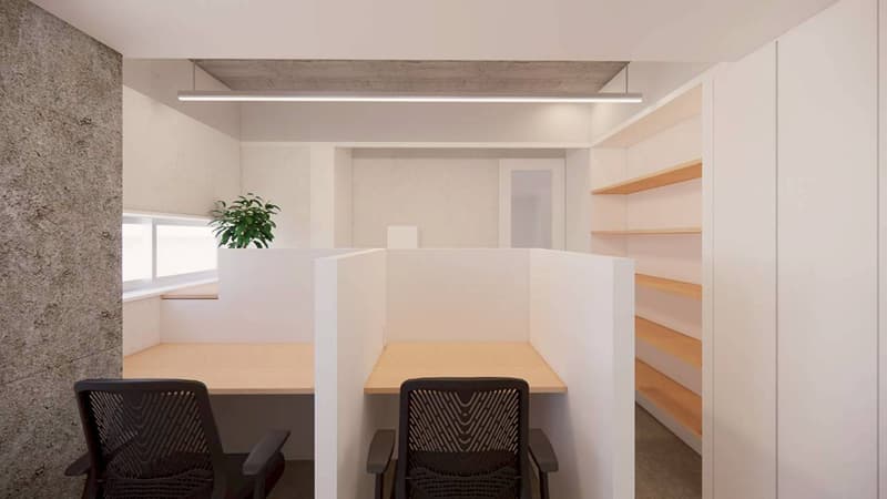 コンクリートの壁と白いパーティションで仕切られた、観葉植物のある2席のワークスペース