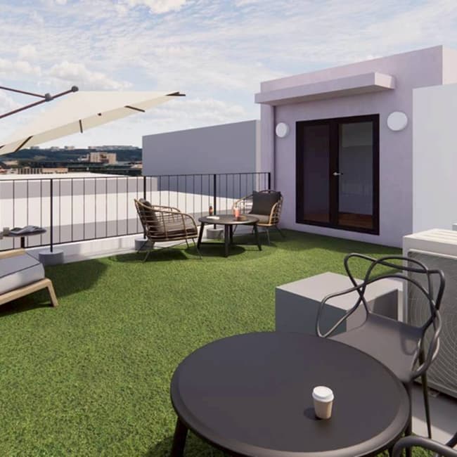 人工芝とパラソル付きのテーブルセットが設置された、開放的な屋上のリラックススペース